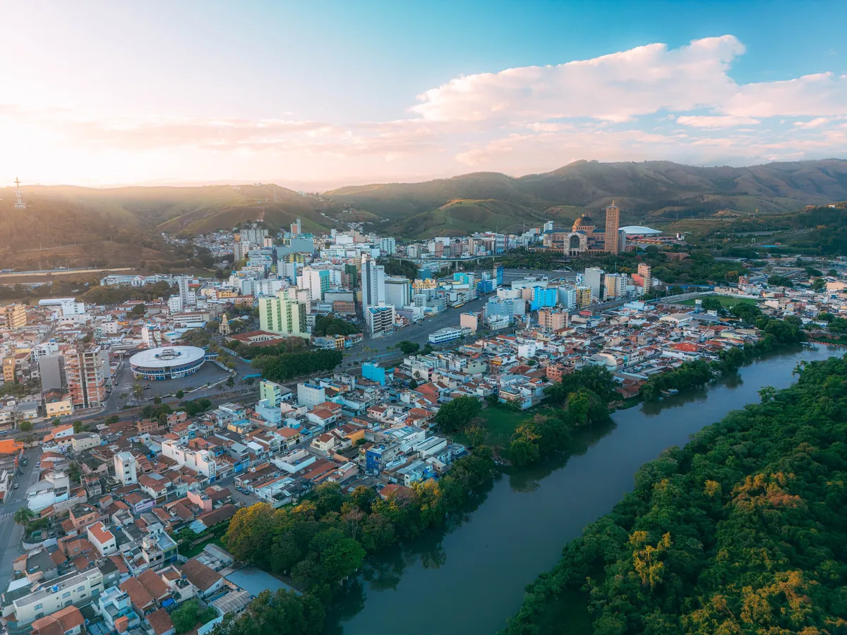 Vista aérea de Aparecida, com o Santuário Nacional, o rio Paraíba do Sul e a serra ao fundo (foto real de drone)